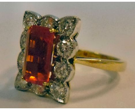 A gold coloured metal, square set, orange stone ring, surrounded by diamonds