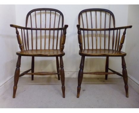 A pair of late 19thC ash and elm framed Windsor chairs, each having curved, level arms, turned spindles and a moulded seat, r