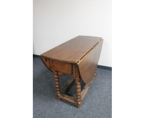 An antique oak gate leg table on bobbin turned legs