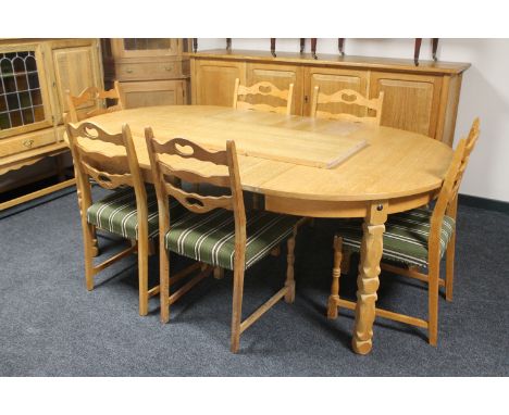 A circular blonde oak extending table with three leaves and six ladder back chairs 