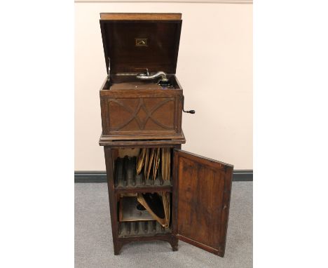 An oak cased HMV gramophone on cabinet containing a quantity of 78's 