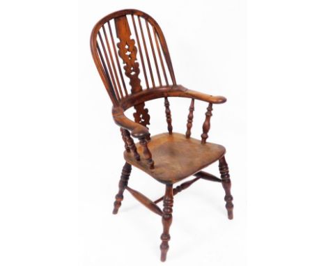 A Victorian yew and elm Windsor chair, with a carved splat, scrolling arms, solid saddle seat, raised on turned legs united b