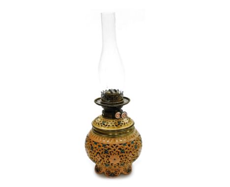 An early 20thC pottery oil lamp, with a clear glass chimney, the base with reticulated floral decoration, blues and pinks, la