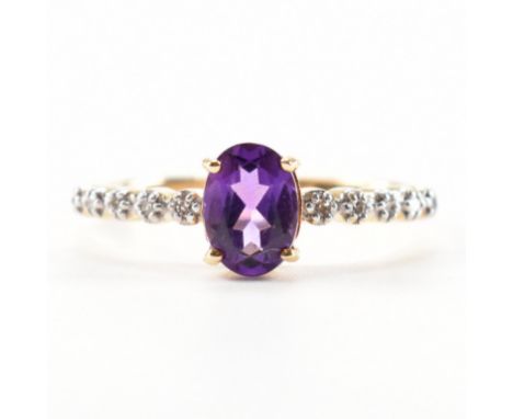 A hallmarked 9ct gold amethyst and diamond ring. The ring set with an oval cut amethyst having single cut diamond shoulders t