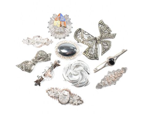 An assorted collection of sterling silver pin brooches. The lot to include; a punched design marcasite set bow, two black sto