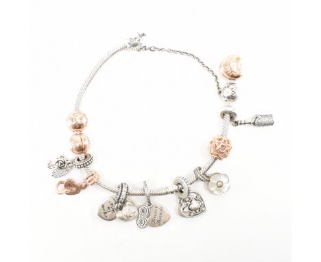 A Pandora silver and gold plated charm bracelet. The snake chain having a gold plated heart clasp with nine charms and a safe