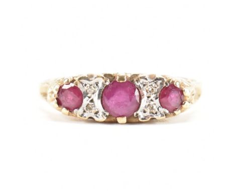 A hallmarked 9ct / 375 yellow gold, ruby & diamond cluster ring. The ring having a central round cut ruby flanked by two acce