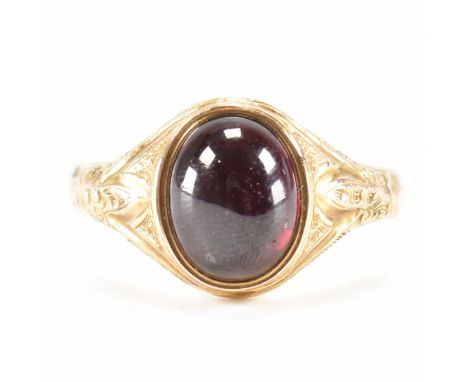 A hallmarked 15ct gold and garnet signet ring. The ring set with an oval cut garnet cabochon to scrolled decorated shoulders.