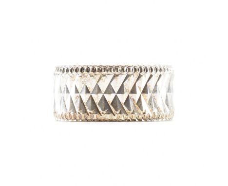 A hallmarked 9ct white gold band ring. The ring having chevron diamond cut decoration framed by beaded edges.&nbsp; Hallmarke