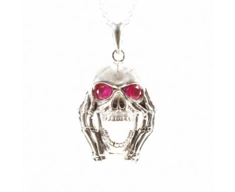 A sterling silver &amp; ruby skull necklace pendant &amp; chain. The pendant in the form of a screaming skull with skeletal h