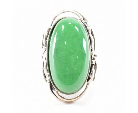 A 925 silver &amp; green jade style stone set ring. The ring having an oval cabochon of green stone to foliate prill design s