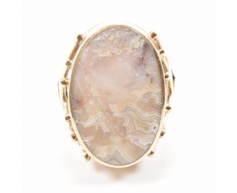 A hallmarked 9ct gold agate set ring. The ring being set with an agate panel with open work mounted shoulders. Hallmarked She