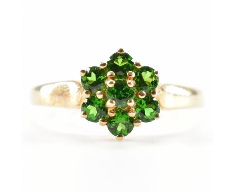 A hallmarked 9ct yellow gold &amp; green stone cluster ring. The ring having a central round cut green stone surrounded by a 