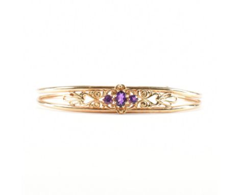 A hallmarked 9ct yellow gold &amp; amethyst cuff bangle. The bangle having three graduating amethysts to the centre on a spli