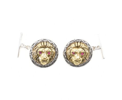 A pair of sterling silver two tone ruby set lion cufflinks. The cufflinks having a silver tone Greek key border encompassing 
