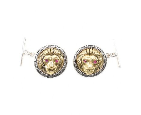 A pair of sterling silver two tone ruby set lion cufflinks. The cufflinks having a silver tone Greek key border encompassing 