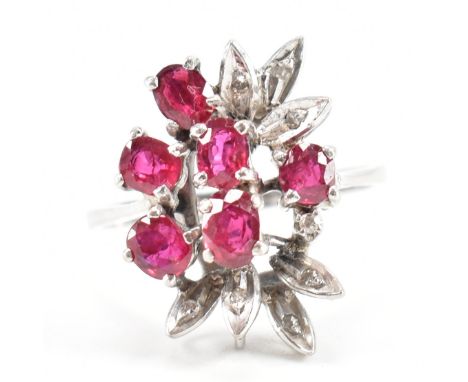 An 18ct white gold ruby and diamond cluster ring. The ring set with six oval cut rubies having diamond accents to foliates to