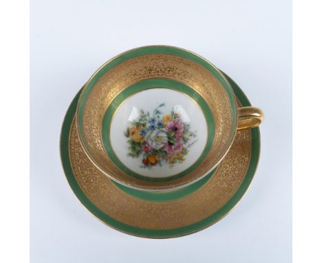 A stunning two-piece set including a porcelain cup and matching saucer, both elegantly adorned with an ornate gilted floral b