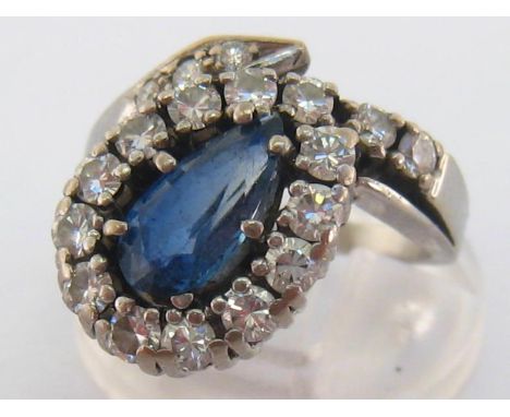 A sapphire and diamond ring, the off set pear cut sapphire approx. 1.06 carat, in a coiled surround of brilliants, the white 
