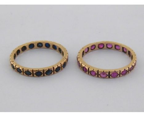 A pair of eternity rings, the first rub over set with a band of sapphires, the second similarly set with rubies, mounted in y