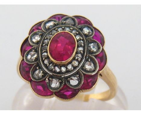 A synthetic ruby and diamond plaque ring, the cluster centring on an oval cut 5.5 x 4mm ruby, in a surround of rose cuts and 