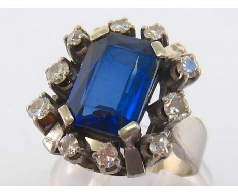 A diamond and synthetic sapphire dress ring, the large rectangular cut stone 12.8 x 9.5mm, in a spaced surround of brilliants