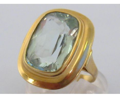 An aquamarine dress ring, the large rectangular cushion cut stone 7.97 carats, in a broad bezel rub over surround, the shank 