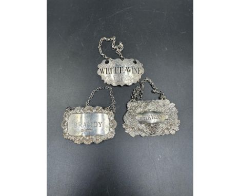 A selection of three silver decanter labels, differing styles but for White Wine, Sherry and Brandy
