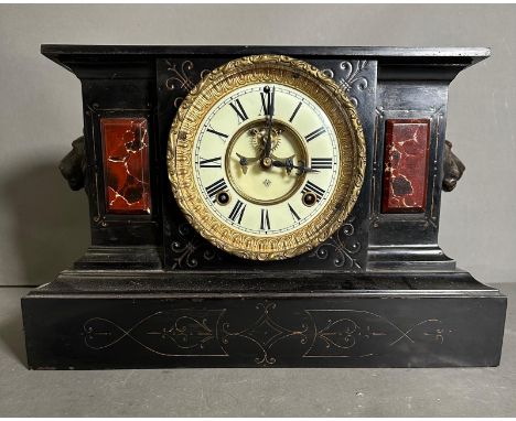 An eight day mantel clock by Ans0nia with enamel face and lions heads to side 