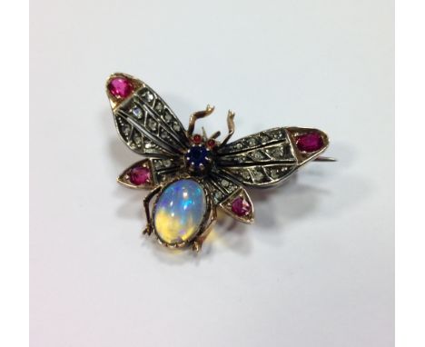 An opal, diamond, ruby and sapphire set butterfly brooch, the oval pale opal cabochon body, with claw set sapphire thorax and