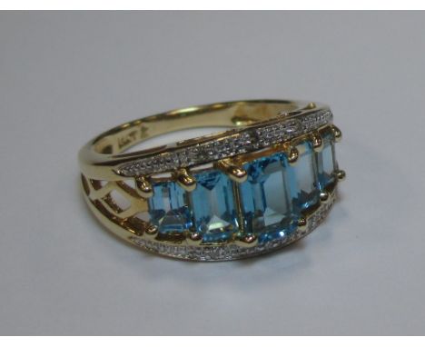 A blue topaz and diamond ring, the five graduated emerald cut topaz, claw set with a narrow channel of white metal to either 