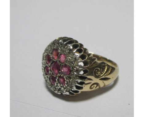 A ruby and diamond cluster ring, the broad flat head of the ring set with eight rubies and surrounded by a ring of small roun