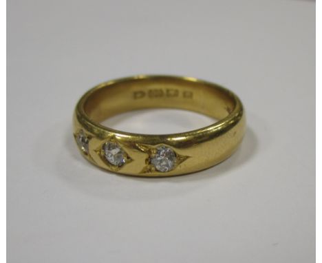 A 22ct three stone diamond ring, the wide band approx. 5.5mm wide set with three small old round brilliant diamonds, hallmark