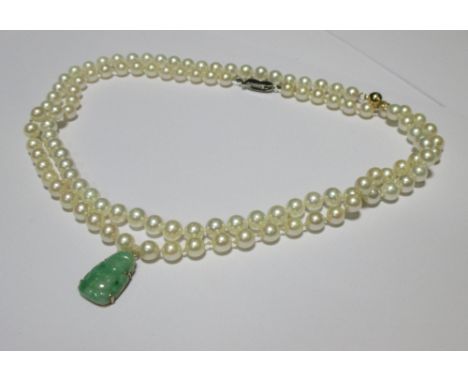 A cultured pearl necklace with a carved jade budha pendant 2cm long, together with a second strand of cultured pearls with a 