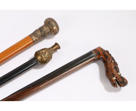 Walking sticks, to include a Chinese example with dragons to the capped top, another with a gilt figure his hat forming a lig
