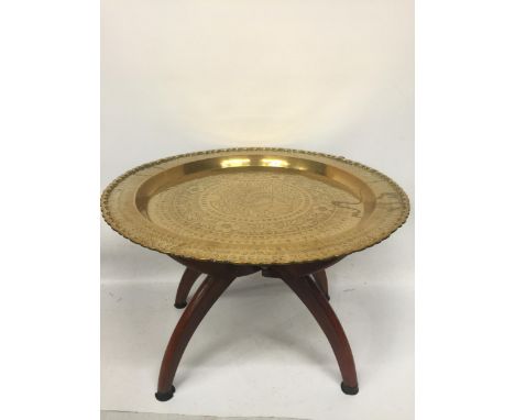 A VINTAGE MIDDLE EASTERN DESIGN BRASS TRAY ON WOODEN STAND 