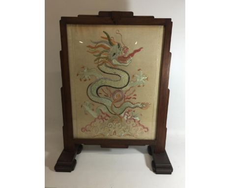 AN OAK FRAMED SILK DRAGON DESIGN FIRESCREEN 