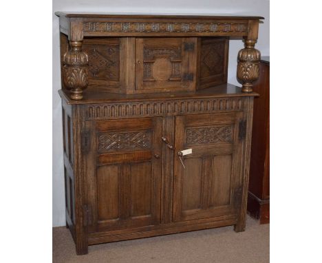 A 17th Century style carved oak buffet, with single door to top section flanked by carved cup and cover supports, panel cupbo