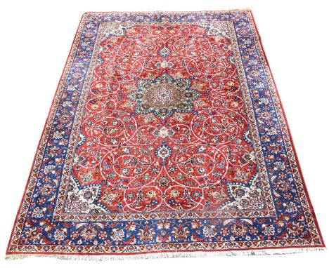An Isfahan carpet, with central medallion surrounded by floral scrolls on a red ground, 414 x 214cms.