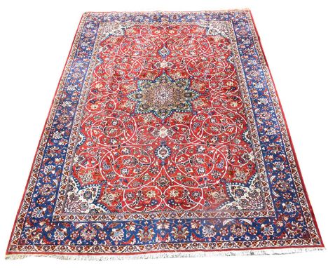 An Isfahan carpet, with central medallion surrounded by floral scrolls on a red ground, 414 x 214cms.