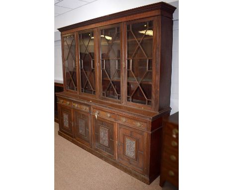 A late Victorian carved mahogany library bookcase, the upper section with dentil cornice and plain frieze above four glazed a