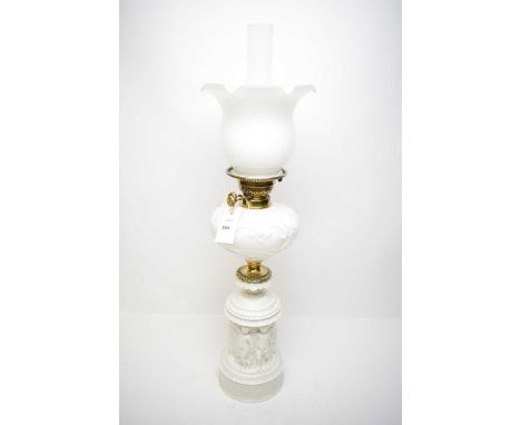A Victorian milk glass and brass oil lamp, the base moulded with putti frieze, opaque glass reservoir and shade, clear glass 