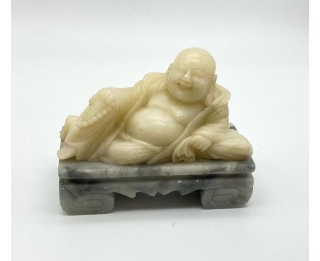 A VINTAGE WHITE JADE BUDDHIST FIGURE RECLINING ON MARBLE BASE.   1.83kgs   15 x 12cms 