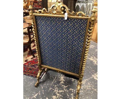 A BLUE GROUND TEXTILE FIRE SCREEN WITHIN A GILT FRAME FLANKED BY BARLEY TWIST COLUMNS ON PAIRS OF LEGS WITH SCROLL FEET