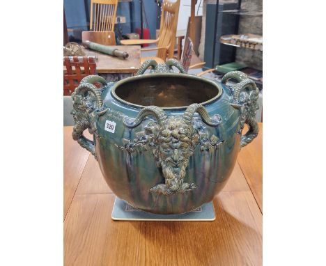 A CLEMENT MASSIER GREEN GLAZED MAJOLICA PLANTER WITH FOUR SATYR MASK HANDLES WITH THEIR HORNS RESTING ON THE RIM.   H 35.5cms