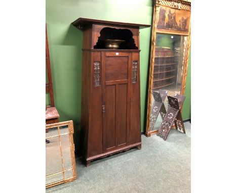 AN ARTS AND CRAFTS OAK WARDROBE WITH HOOKS FLANKING THE OPEN SHELF TOP, TWO METAL PANELS FLANKING TO THE TOP OF THE DOOR WITH