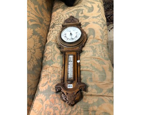 AN OAK CASED ANEROID BAROMETER WITH THE DIAL BELOW A MERCURY THERMOMETER