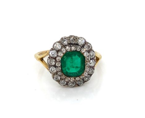 A LATE 19th CENTURY CIRCA 1870 EMERALD AND DIAMOND CLUSTER RING SET WITH A PRINCIPLE EMERALD CUT EMERALD MEASURING APPROXIMAT