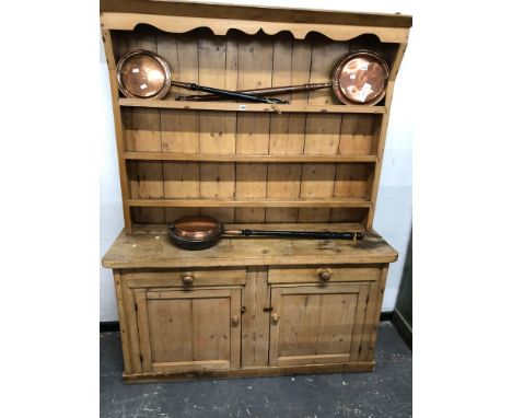 AN ANTIQUE PINE DRESSER THE ENCLOSED SHELF BACK ABOVE PAIRS OF DRAWERS OVER DOORS AND THE PLINTH FOOT.   W 147 x D 44 x H 190