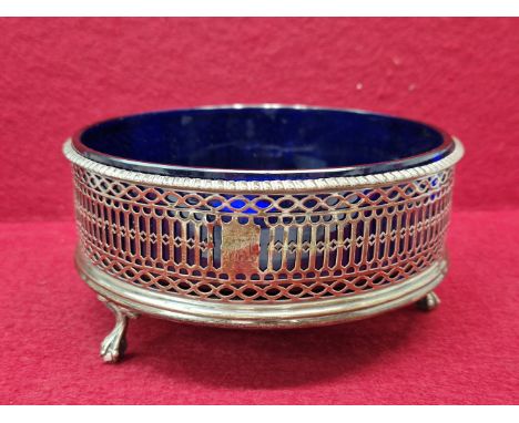 A SILVER TRIPOD COASTER AND BLUE GLASS LINER, LONDON 1775, INITIALLED TO ONE OF THE PIERCED SIDES.&nbsp; &nbsp;Dia. 17cms.